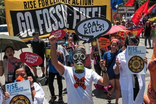 Menschen mit Gasmasken in einem Demonstrationszug, auf Transparenten steht "Coal Kills" und "Go Fossil Free!"