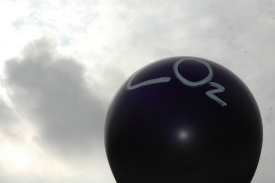 Ein schwarzer Ballon mit der Aufschrift "CO₂" vor einem Wolkenhimmel.