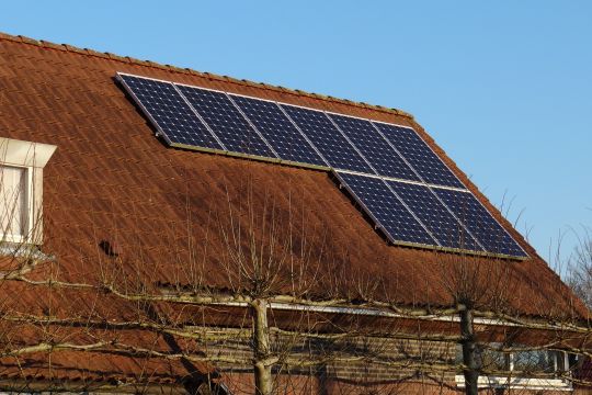 Ein traditionelles ländliches Hausdach mit Solarmodulen.